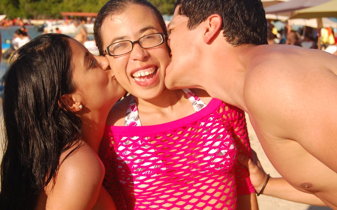 Foto de tres personas, dos de ellas besando a la tercera en la mejilla.
