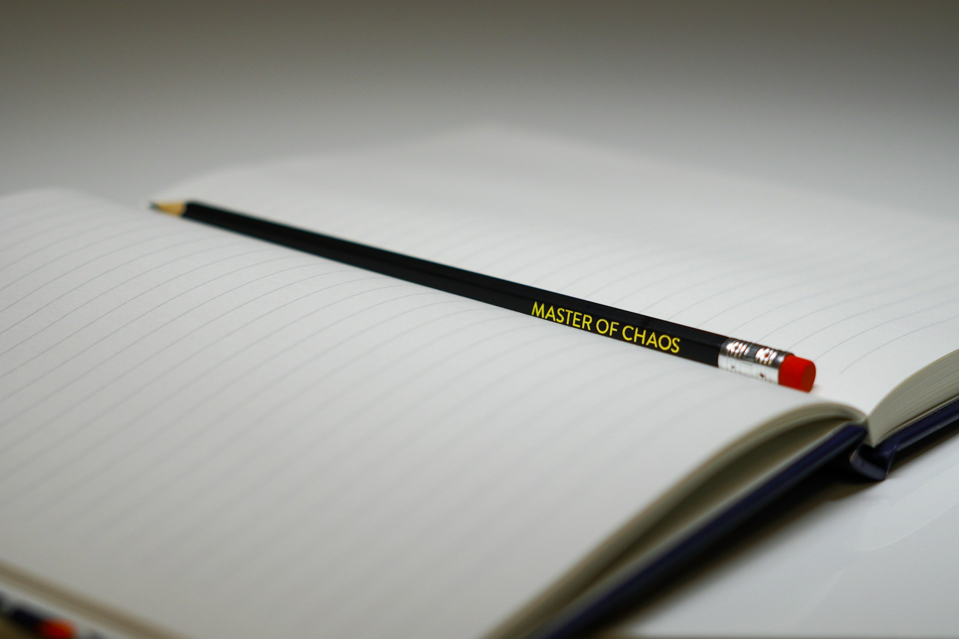 Black pencil resting diagonally across the lined pages of an open notebook.